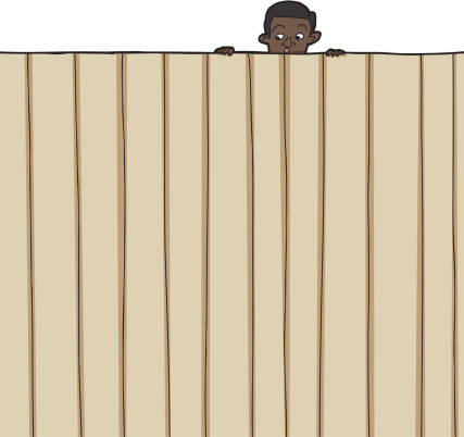 Amazed male child looking over wooden fence