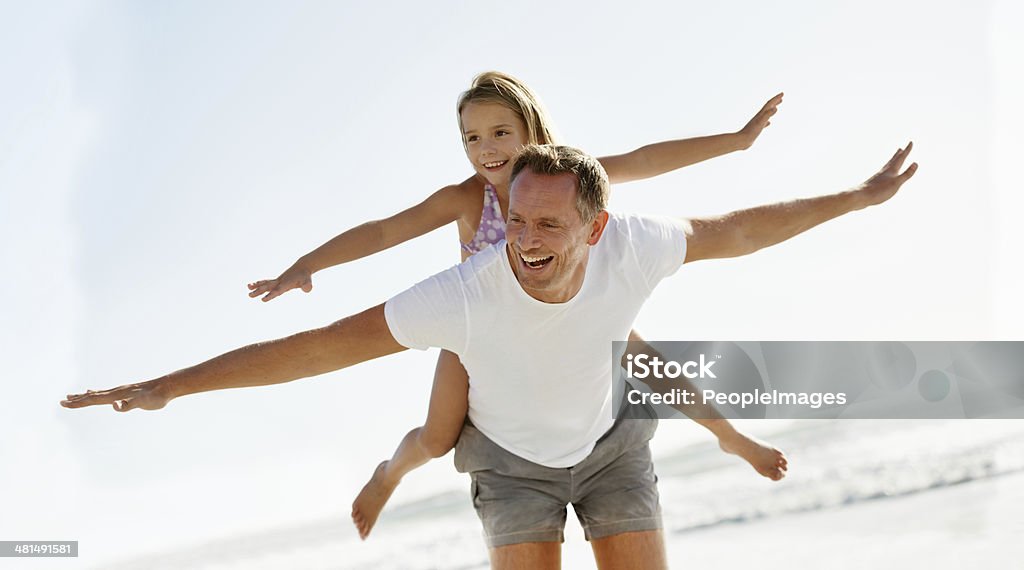 They make a good team! Shot of a young girl on her father's back at the beach Father Stock Photo