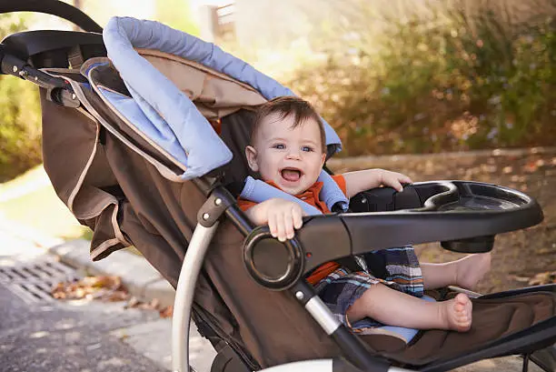 Portrait of a baby boy sitting in a stroller outside