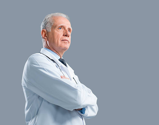 Senior Doctor Portrait Senior doctor looking away on gray background. doctor head stock pictures, royalty-free photos & images