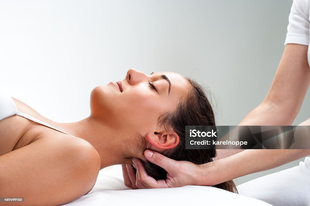 Physiotherapist pressing back of womans head. Close up of  chiropractor pressing back of woman's head. Therapist doing healing massage with fingers at back of neck. Osteopath Stock Photo