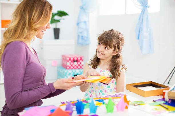 istock Mother and daughter making origami. 481500953