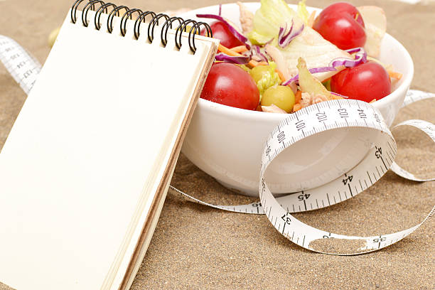 Salad, tape measure and shells on sand