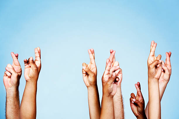 istock Many superstitiously crossed fingers raised against sky background 481507391