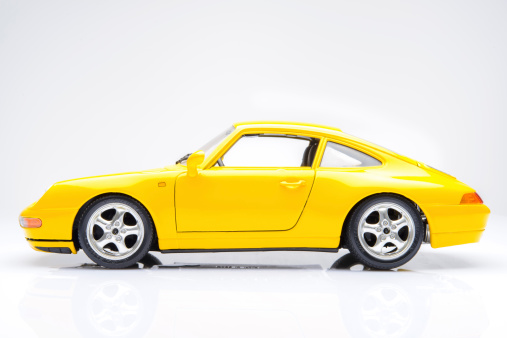 Kampen, The Netherlands - March 25, 2014: Yellow Porsche 911 (993) sports car model by Bburago isolated on a white background.