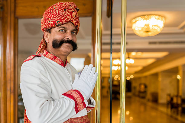 Indian Concierge Welcome Guest at Hotel Entrance India Indian Concierge, Doorman dressed in traditional indian clothes welcomes the guest at the entrance with the typical indian welcome gesture and a happy smile. Agra, India. door attendant photos stock pictures, royalty-free photos & images