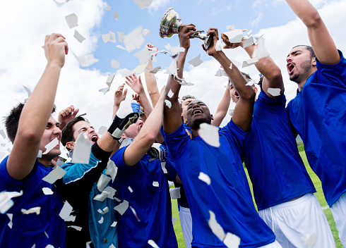 Soccer team celebrating their victory and holding the cup
