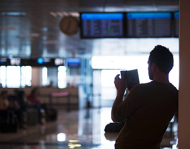 молодой человек в аэропорту собирается для отдыха - timeboard стоковые фото и изображения