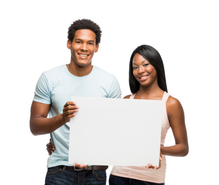 A happy young couple holding a white sign together. Isolated on a white background.
