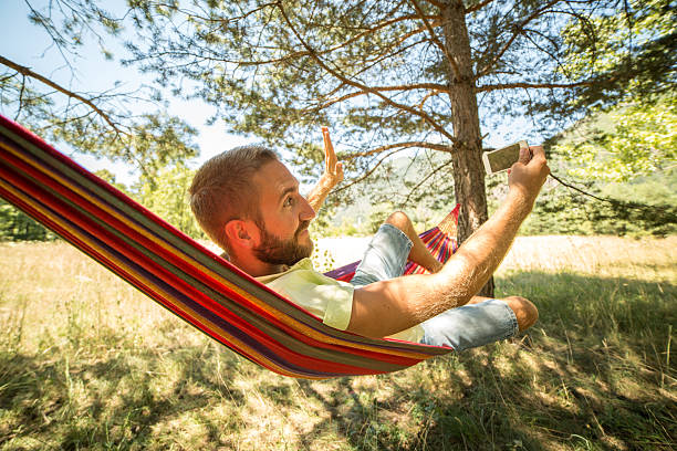 istock Fun young man on hammock taking selfie-Summer 481523698