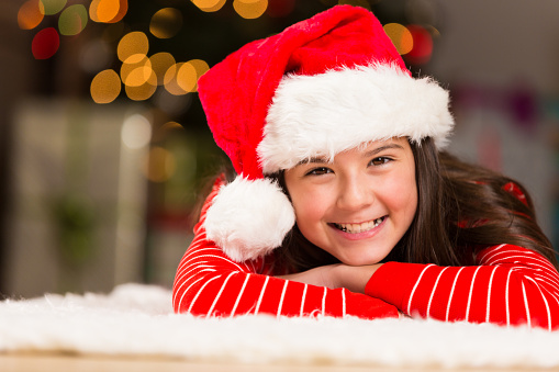 Adorable preteen girl wearing Christmas pajamas and Santa hat