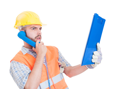 Confident contractor or builder using phone and holding clipboard isolated on white background