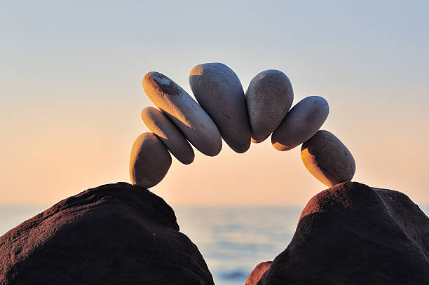 Bending Arc of pebbles between of the stones on the coast balance stock pictures, royalty-free photos & images