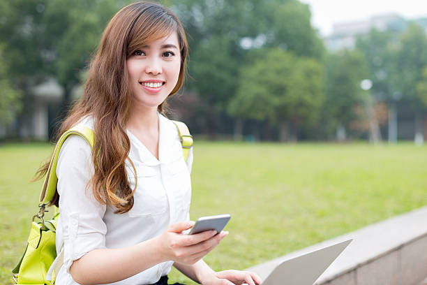 linda asiática feminino studen utilizar o telemóvel no campus - studen imagens e fotografias de stock