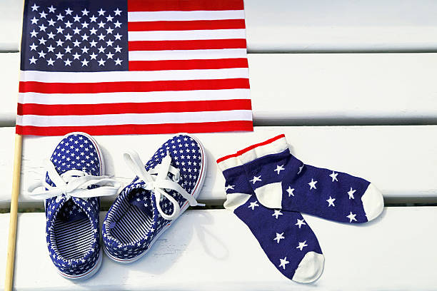 American flag, children's sneakers, socks on white background. United States of America flag, american children's sneakers and socks on white wooden background. Kid’s shoe, footgear, flag. Empty place for message. Copy space. Freedom, fashion concept. usa flag shoes stock pictures, royalty-free photos & images