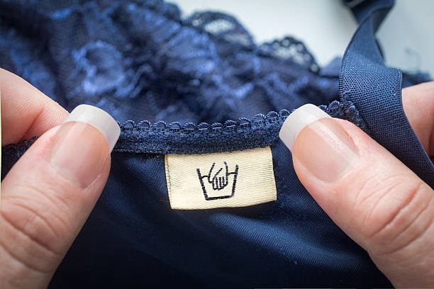 Woman pov holding lingerie with an handwash label Clothing washing label which  states that it is handwash. bra stock pictures, royalty-free photos & images