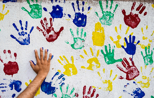 A close-up view of the messy hands of one Caucasian abstract artist, using his hands for painting with oil colors on canvas.