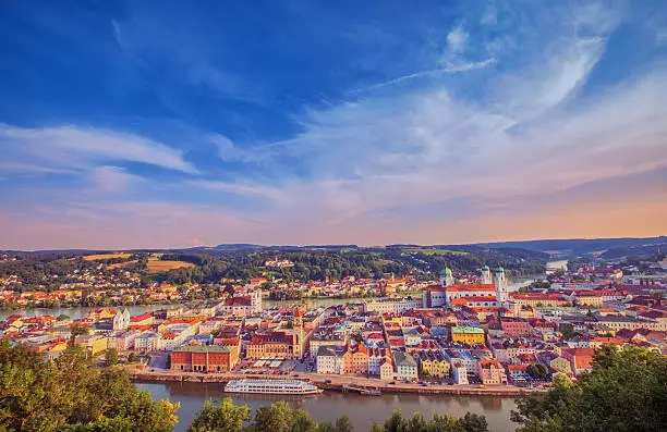 Picturesque panoramic view over Passau on a beautiful summer evening. A signtseeing boat anchored in front of the town hall.