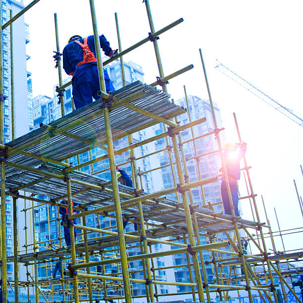 working on scaffolding Construction workers working on scaffolding construction skyscraper machine industry stock pictures, royalty-free photos & images