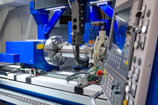 Detailed view of a modern machining workspace, showcasing precision engineered metal parts in the foreground with a CNC machine operating in the background.