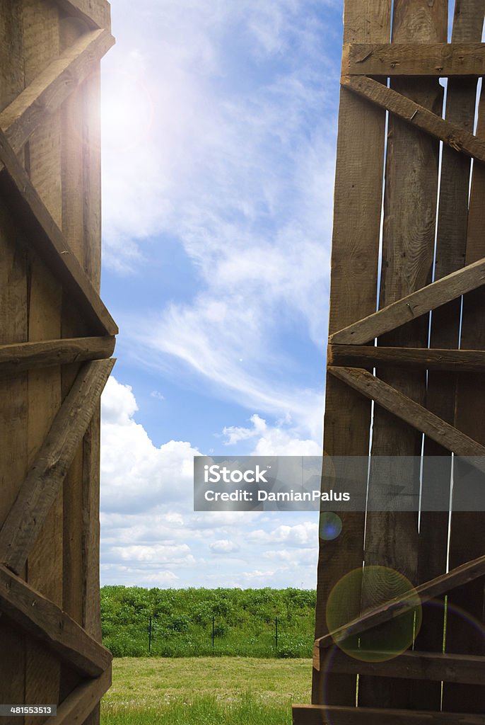 An open gate of a barn An open gate of a barn with a view of the sky and grass Opening Stock Photo