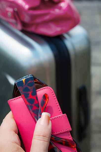istock Pink phone and sun glasses black bag on silver suitcase 481555926