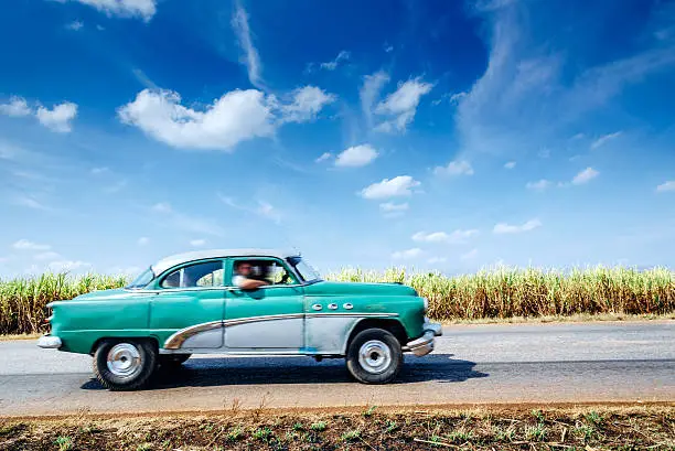 Vintage car driving on rural road, Cuba