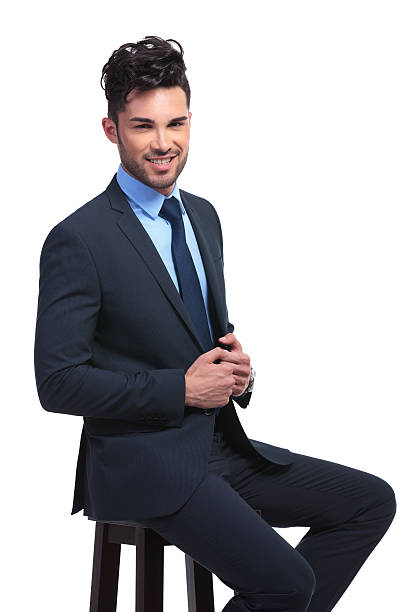 istock smiling young business man sitting on a stool 481560653