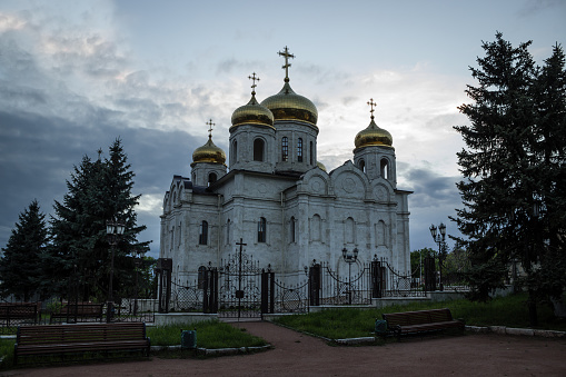 Orthodox church in the evening surrounded by trees on the background of cloudy sky