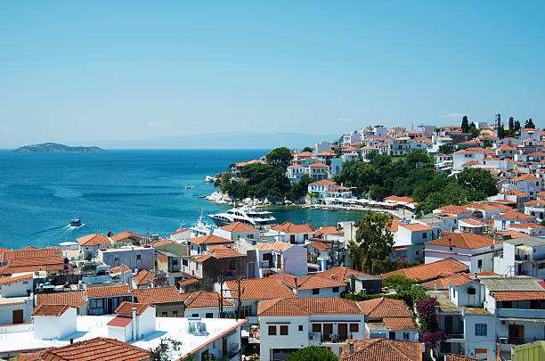 The old town area of Skiathos including the old port area where a modern super yacht is currently berthed. The white buildings with red roofs is typical of Greece and this area of the Aegean sea.   