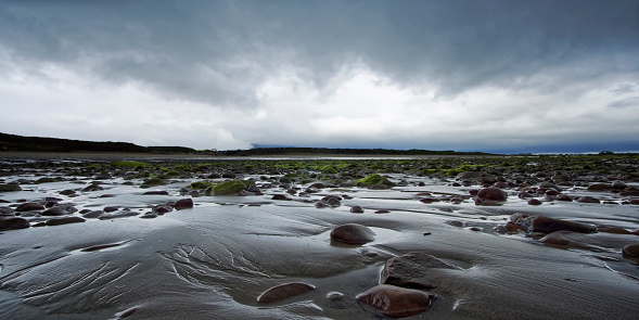 Low angle view on rocks and sand with dramatic sky at White Rocks Beach in Northern Ireland.