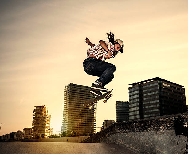 Female young skateboarder jumping in skatepark in the city Female teenager skateboarder jumping in skateboard park at sunset skateboarding stock pictures, royalty-free photos & images