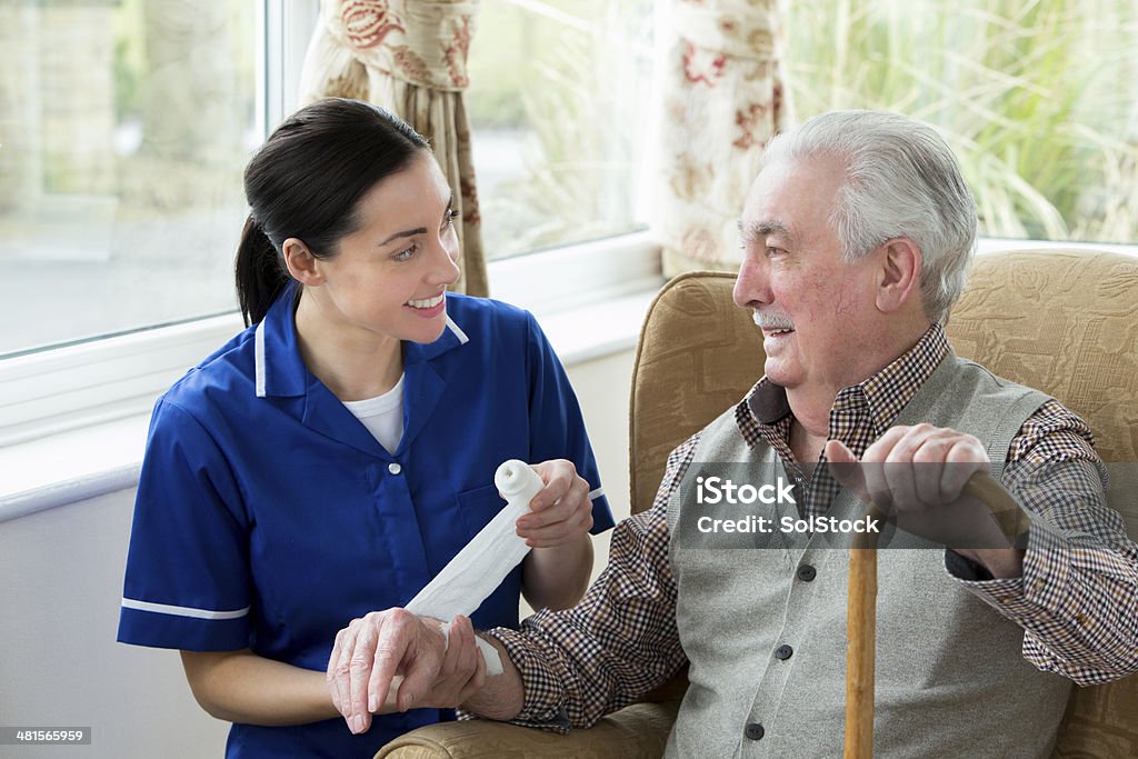 Injury at care Home Nurse bandaging up an injured senior mans arm in retirement home Wound Stock Photo