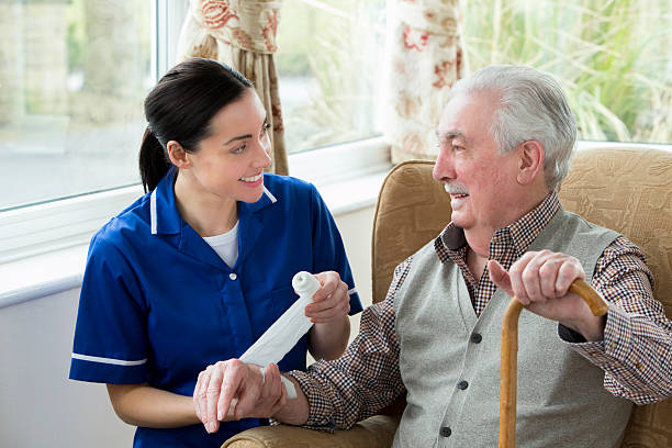 Injury at care Home Nurse bandaging up an injured senior mans arm in retirement home wounded stock pictures, royalty-free photos & images