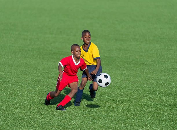 Male football players running during match on football pitch.