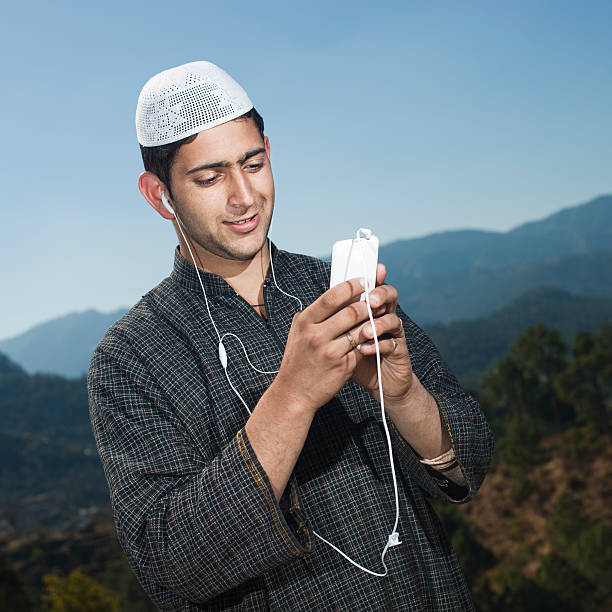 istock Kashmiri young man in mountains using phone with headphones on. 481567220