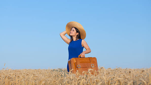 istock girl with suitcase at wheat field 481567826