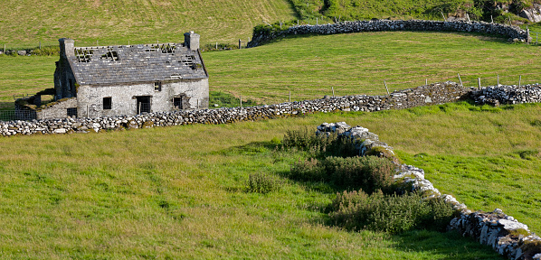 Pasture with stone wall and rund-down home at west coast of Ireland.