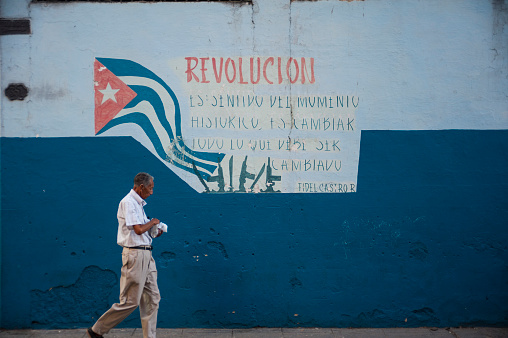 Havana, Cuba - May 19, 2015: A man walks past a Revolutionary mural containing a quote by Cuban leader Fidel Castro.