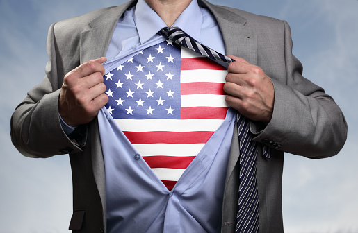Businessman in classic superman pose tearing his shirt open to reveal t shirt with the American flag concept for patriotism, freedom and national pride