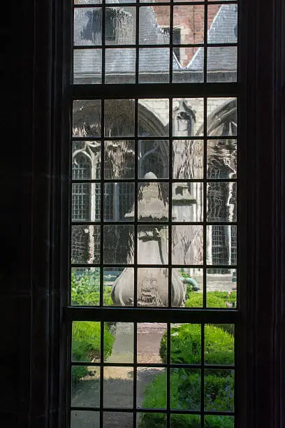 old venetian glass window  view  the historic 14th century  gothic abbey herb garden in middelburg  the Netherlands. The Abbey complex is a dutch national monument and abbey churches and garden are free to visit  for the public.