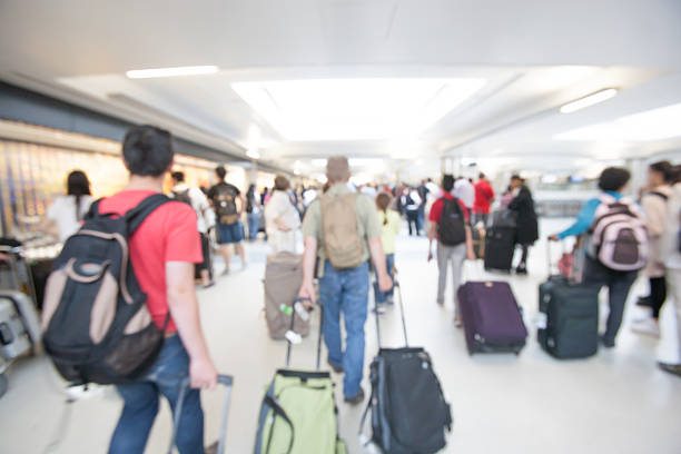 Passengers walking through a busy airport with their luggage