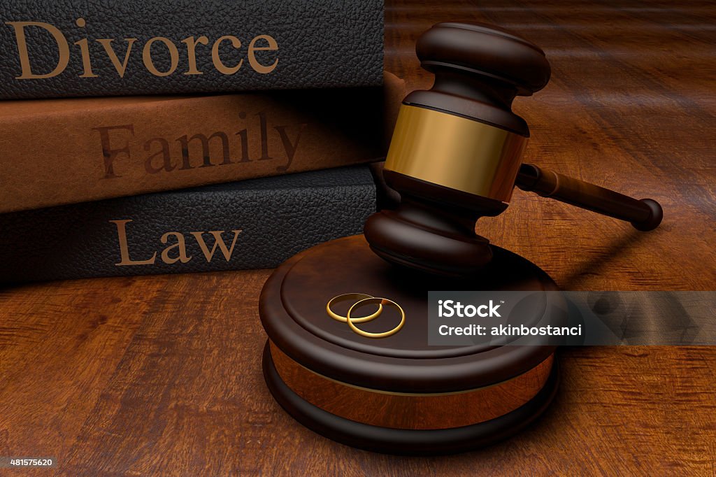 Gavel, divorce law books and wedding rings Stack of three gray textbooks with the words "divorce," "family" and "law" written in gold print.  The textbooks are behind a wooden gavel that is poised above two golden rings. Family Law Stock Photo