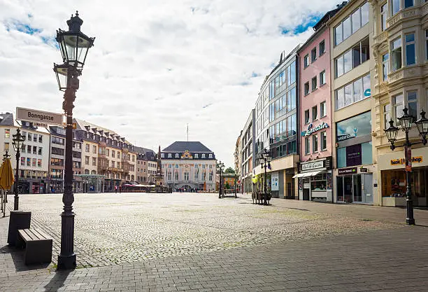 market square in Bonn / Germany with the old town hall  and an obelisk in background. Many restaurants and shops are located around this place. Some tourists are standing in front of the old town hall