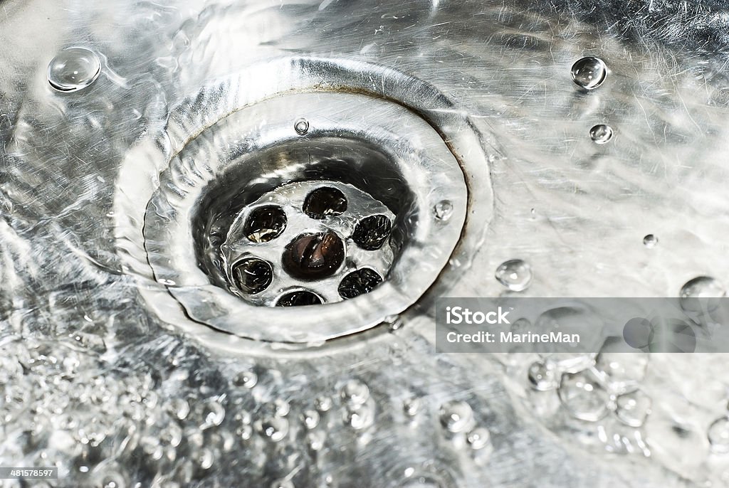 Stainless steel sink plug hole close up with water Drain Stock Photo
