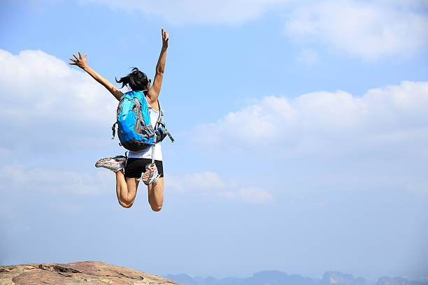 istock cheering woman hiker jumping on mountain peak 481585228