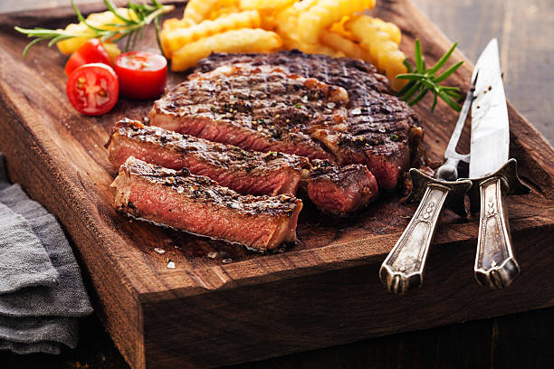 Sliced Steak Ribeye with french fries Sliced medium rare grilled Steak Ribeye with french fries on serving board block on wooden background rib eye steak stock pictures, royalty-free photos & images