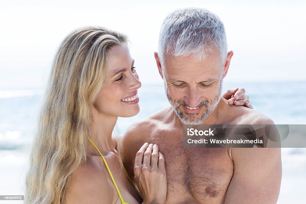 Happy couple standing by the sea and hugging each other Happy couple standing by the sea and hugging each other at the beach 2015 Stock Photo