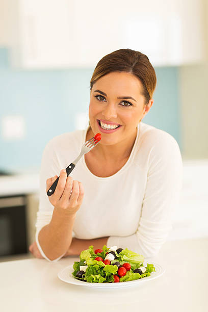 istock young woman eating green salad 481610078