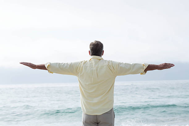 istock Thoughtful man standing by the sea arms outstretched 481619916